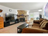 Inviting living room featuring a stone fireplace and a comfortable seating area with a cozy, brown sofa at 14444 E Colorado Dr # 204, Aurora, CO 80012