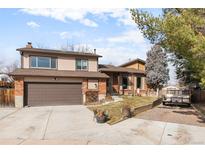 Charming two-story home featuring a brick and beige siding exterior and a well-maintained front yard with a two car garage at 7551 S Garland St, Littleton, CO 80128
