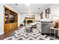 Cozy living room with a fireplace, plush rug, and built in entertainment center at 7551 S Garland St, Littleton, CO 80128