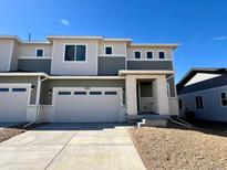 Two-story townhome with neutral siding, large windows, a two-car garage, and a well-maintained front yard at 6605 N Nepal St, Aurora, CO 80019