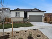 Charming single-Gathering home featuring a stone facade, gray garage door, and well-manicured front yard at 17156 W 92Nd Loop, Arvada, CO 80007