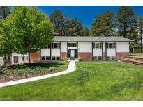 Charming ranch-style home features a lush front yard with mature trees and walkway leading to the front door at 33589 Robin Ct, Elizabeth, CO 80107
