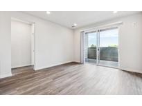 Bright living room features sliding glass doors to balcony and wood-look flooring at 485 Interlocken Blvd # 201, Broomfield, CO 80021