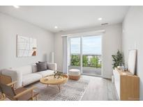 Bright living room with hardwood floors, sliding glass doors to a balcony, and modern furnishings at 485 Interlocken Blvd # 201, Broomfield, CO 80021