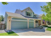 Charming two-story home featuring a three car garage, brick accents, a covered porch, and professionally landscaped front yard at 15432 Greenstone Cir, Parker, CO 80134