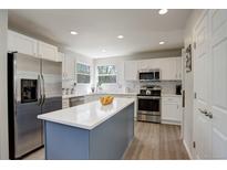 Modern kitchen with stainless steel appliances, white cabinets, island with seating, and stylish backsplash at 15432 Greenstone Cir, Parker, CO 80134