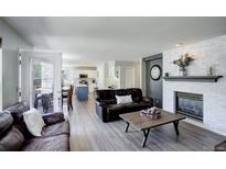 Bright living room features a brick fireplace, modern flooring, and an open floor plan to the kitchen at 15432 Greenstone Cir, Parker, CO 80134