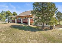 Spacious home features a covered deck, mature tree, and a well-maintained lawn in a serene setting at 43097 Taos Trl, Elizabeth, CO 80107
