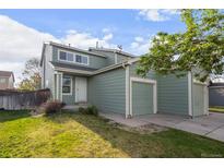 A charming two-story home with a well-maintained lawn, white door, and attached two-car garage at 747 Mockingbird St, Brighton, CO 80601