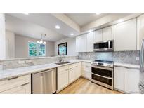 Modern kitchen featuring white cabinetry, stainless steel appliances, and granite countertops at 12919 W Burgundy Dr, Littleton, CO 80127