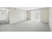 Bright living room with neutral walls, carpeted floor, and sliding glass door at 7395 E Quincy Ave # 207, Denver, CO 80237