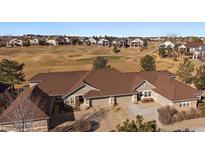 Stunning aerial view of a tan home with brown roof on a golf course surrounded by a residential community at 7679 S Biloxi Way, Aurora, CO 80016