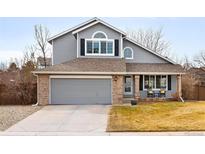Charming two-story home with a gray exterior, brick accents, a two-car garage, and a well-maintained front yard at 9271 Wheeler Ct, Highlands Ranch, CO 80126