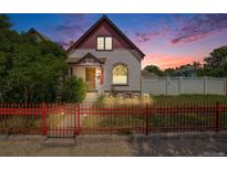 Charming home with red trim, decorative fence, landscaped yard and nice sunset at 3106 N Franklin St, Denver, CO 80205