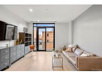 Bright living room features hardwood floors, a modern sofa, and a large window with an expansive city view at 1901 Wazee St # 305, Denver, CO 80202