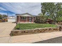 Charming brick home featuring a well-maintained lawn and a detached garage at 1325 Elder St, Denver, CO 80221