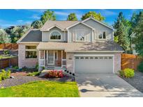 Charming two-story home featuring a covered porch, lush landscaping, and an attached two-car garage at 11932 W 56Th Cir, Arvada, CO 80002