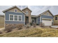 Charming two-story home featuring a blue facade with stone accents and a well-manicured front yard at 12650 W Big Horn Cir, Broomfield, CO 80021