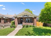 Charming brick home featuring a cozy front porch and well-maintained lawn on a sunny day at 3332 N Vine St, Denver, CO 80205