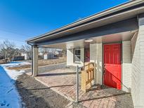 Charming brick front porch and vibrant red door offer a welcoming entry to this home at 5665 Niagara St, Commerce City, CO 80022