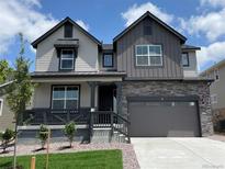 Beautiful two-story home with stone accents, a covered porch, and a well-manicured lawn at 747 Raindance St, Erie, CO 80516