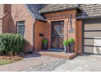 Charming brick home featuring a decorative security door, lush landscaping, and a well-maintained facade at 629 Bellaire St, Denver, CO 80220