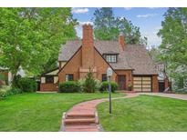Charming brick home featuring a beautiful lawn, mature trees, and welcoming red brick pathway to the front door at 629 Bellaire St, Denver, CO 80220