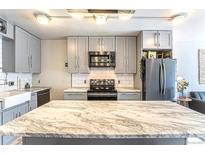 Bright kitchen features gray cabinets, subway tile backsplash, and center island with marble countertop at 1050 N Corona St # 206, Denver, CO 80218
