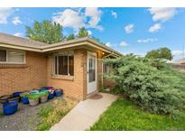 Charming home exterior with brick facade, walkway, and garden bed with bright blue pots leading to the front door at 4787 Carr St, Wheat Ridge, CO 80033
