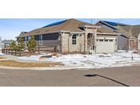 Charming single-story home featuring a stone and wood exterior, solar panels, and a two-car garage at 8885 S Tibet Ct, Aurora, CO 80016