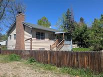 Charming home featuring a brick chimney, wooden fence, and lush landscaping at 1251 Lee St, Lakewood, CO 80215
