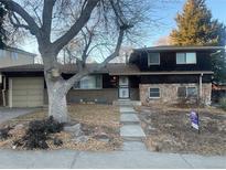 Charming two-story home with a unique facade featuring stone and brick accents, complemented by mature trees and landscaping at 2995 S Whiting Way, Denver, CO 80231