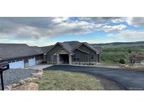 Beautiful single Gathering home with gray siding, stone accents, and a well-manicured lawn at 5489 Country Club Dr, Larkspur, CO 80118