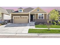 Charming single-Gathering home showcasing a landscaped front yard, attached garage and inviting entry way at 18340 W 85Th Dr, Arvada, CO 80007