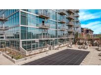 Modern glass condominium building featuring private balconies and a community pool at 1700 Bassett St # 820, Denver, CO 80202