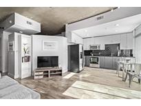 Open living area featuring TV, shelving, and modern kitchen at 1700 Bassett St # 820, Denver, CO 80202