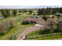 Sprawling ranch-style home with an attached garage, set on a large lot with mature trees and green pastures at 2464 Remington Rd, Elizabeth, CO 80107