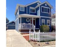 Charming two-story home with blue siding, white trim, a white picket fence, and a detached garage at 8146 E Harvard Cir, Denver, CO 80231