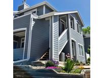 Charming gray two-story home with stairs to entry and beautifully landscaped flower beds at 8500 E Jefferson Ave, Denver, CO 80237