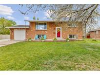 Charming brick home with lush green lawn, bright red door, and inviting blue Adirondack chairs at 4544 W 65Th Ave, Arvada, CO 80003