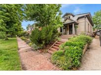 Charming two-story brick home with landscaped front yard and inviting porch steps, framed by mature trees at 2253 N Williams St, Denver, CO 80205