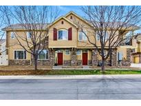 Townhouse exterior with stone accents, red doors, tan siding, and leafless trees in the front at 9980 W Jewell Ave # B, Lakewood, CO 80232