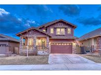 Two-story home featuring stone accents, covered porch, and a two-car garage in a suburban neighborhood at 10104 Nadine Ave, Parker, CO 80134