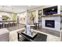 Open concept living room with a fireplace, kitchen, and stairs to a second level at 10104 Nadine Ave, Parker, CO 80134