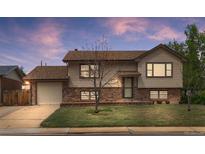 Charming two-story home with a brick and siding exterior and well-maintained front yard at dusk at 1549 Dean Dr, Northglenn, CO 80233
