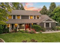 Charming two-story home featuring a landscaped yard and a welcoming front porch with beautiful sunset at 6128 S Coventry E Ln, Littleton, CO 80123