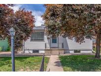 Charming home with white siding and a well-manicured lawn, framed by vibrant, mature trees. A welcoming entrance at 2845 Eaton St, Wheat Ridge, CO 80214