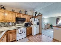 Bright kitchen featuring wooden cabinets, modern appliances, and a colorful backsplash at 12425 Bellaire Dr, Thornton, CO 80241