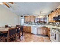 Cozy eat-in kitchen boasts stainless steel appliances, wood cabinets, and a stylish backsplash at 12425 Bellaire Dr, Thornton, CO 80241