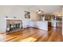 Bright living room featuring a brick fireplace, hardwood floors and a ceiling fan at 12425 Bellaire Dr, Thornton, CO 80241